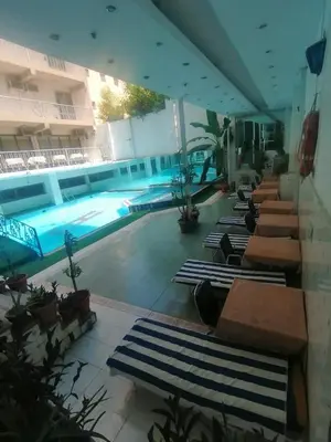 a pool with a row of chaise lounges in a building at Windsor Hotel Luxor \u60a8\u5728\u76e7\u514b\u7d22\u7684\u7b2c\u4e8c\u500b\u5bb6 in Luxor