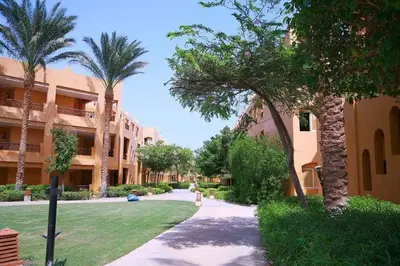 a walkway in front of a building with palm trees at chalet Stella de Mari in Makadi Bey in Hurghada