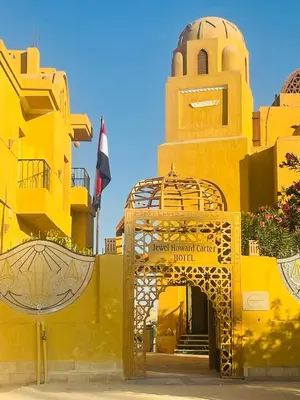 a yellow building with a gate and a tower at Jewel Howard Carter Hotel in Luxor