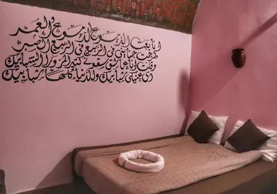 a room with a bed with a sign on the wall at Hadouta Masreya Nubian Guest House in Aswan