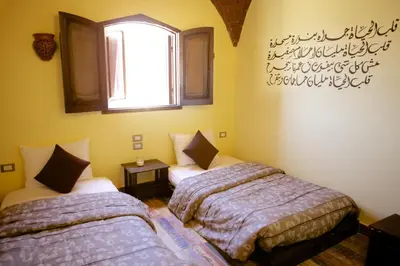 two beds in a room with a window at Hadouta Masreya Nubian Guest House in Aswan