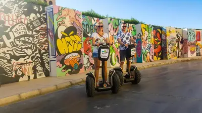 two people on segways in front of a wall with graffiti at Fanadir Hotel El Gouna in Hurghada