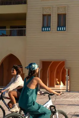 two people riding bikes in front of a building at Fanadir Hotel El Gouna in Hurghada