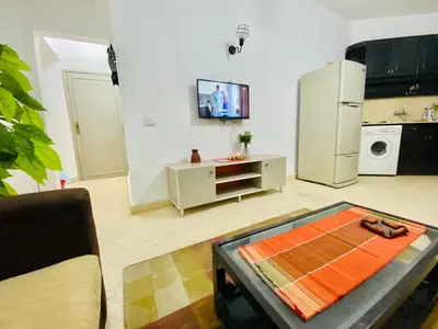 a living room with a table and a refrigerator at Tamburine Chalet with Wi Fi Hurghada center in Hurghada