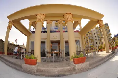 a large building with chairs and tables in front of it at Sphinx Aqua Park Beach Resort in Hurghada