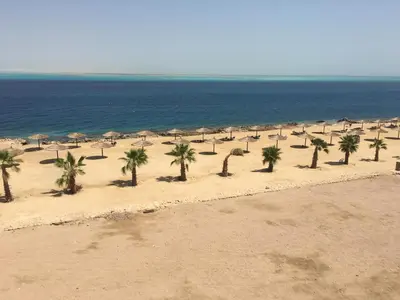 an empty beach with palm trees and umbrellas at Sea View Duplex Villa in Hurghada