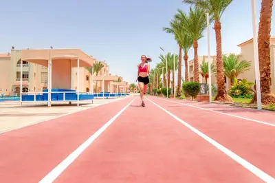 a woman walking down a red road with palm trees at Pickalbatros Aqua Vista Resort - Hurghada in Hurghada