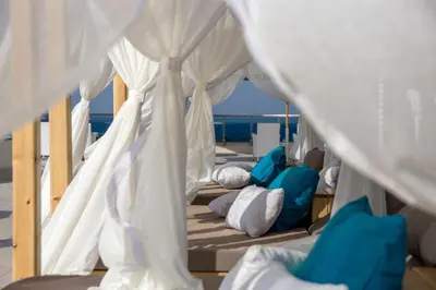 a row of beds with white curtains and blue pillows at Redcon Suites in Hurghada
