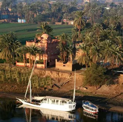 a white boat on the water in front of a house at villa al diwan luxor in Luxor