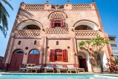 a building with chairs and a pool in front of it at villa al diwan luxor in Luxor