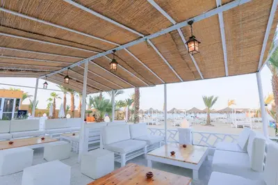 a patio with white chairs and tables and a view of the beach at Lagoonie Lodge & Beach in Hurghada