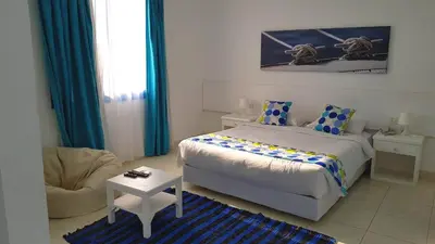 a bedroom with a bed and a chair and a table at Lagoonie Lodge & Beach in Hurghada