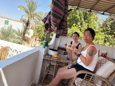 a couple of people sitting on a balcony eating food at Seko Kato Nile View Hostel in Aswan