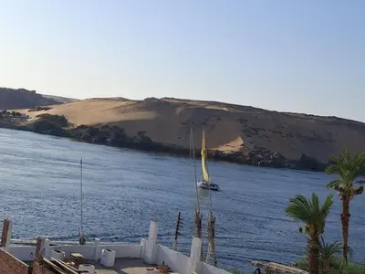 a sail boat in the water with a beach at Seko Kato Nile View Hostel in Aswan