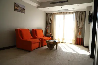 a living room with two orange chairs and a table at Aswan Plaza Hotel in Aswan