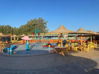 a playground with tables and chairs and umbrellas at Comfortable studio in hotel Karma with private beach and pools family only or female in Hurghada