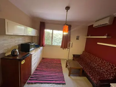 a room with a couch and a kitchen with a window at Comfortable studio in hotel Karma with private beach and pools family only or female in Hurghada