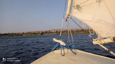 a boat on the water with a sail at felouque avec toilettes in Aswan