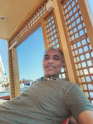 a man is smiling while sitting in a window at felouque avec toilettes in Aswan
