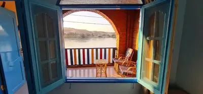 an open window of a balcony with a view of the water at Meshra Katto in Aswan