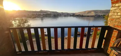 a balcony with a view of a lake with the sunset at Meshra Katto in Aswan