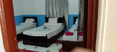 two twin beds in a room with a mirror at El-amin Guest House in Aswan