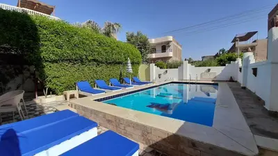 a swimming pool with blue lounge chairs next to a building at Luxor VIP Apartments in Luxor