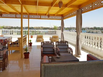 a porch with chairs and tables on a balcony at Luxor VIP Apartments in Luxor