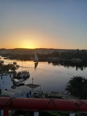 a sunset over a marina with a sail boat in the water at El Prince Guesthouse in Aswan