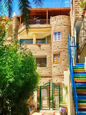 a large brick building with a staircase in front of it at Spring Hotel Luxor in Luxor