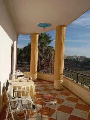 a balcony with tables and chairs and a view of a train at Adam and Eve House in Luxor