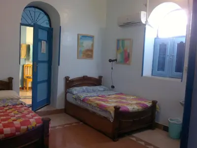 a bedroom with a bed and a blue door at Bet El Kerem Guesthouse in Aswan