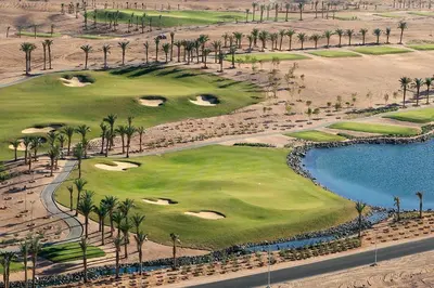 an aerial view of a golf course with palm trees and a pool at JAZ Makadi Saraya Resort in Hurghada