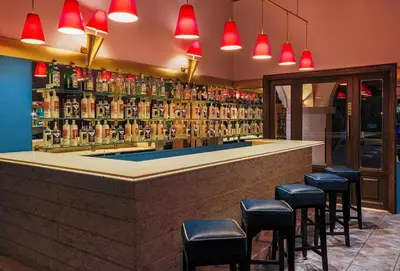 a bar with stools in a room with alcohol bottles at JAZ Makadi Saraya Resort in Hurghada