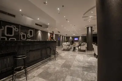 a restaurant with a bar with stools and tables at Shams Prestige Abu Soma (Adults Only) in Hurghada