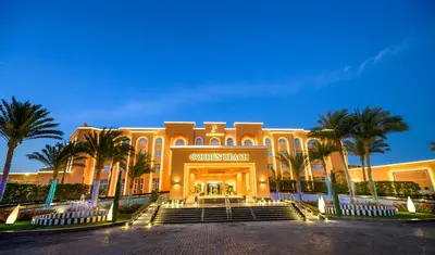a building with palm trees in front of it at Golden Beach Resort in Hurghada