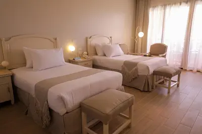 a hotel room with two beds and a chair at Calimera Blend Paradise in Hurghada