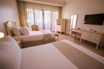 a hotel room with two beds and a television at Calimera Blend Paradise in Hurghada