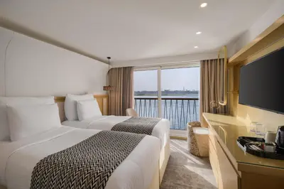 a hotel room with two beds and a large window at Tamr Nile Cruise - 04 Nights Every Monday from Luxor - 03 Nights Every Friday from Aswan in Luxor
