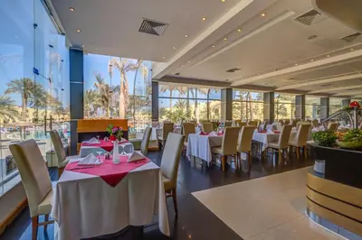a restaurant with white tables and chairs and windows at Palm Beach Resort Families and Couples only in Hurghada