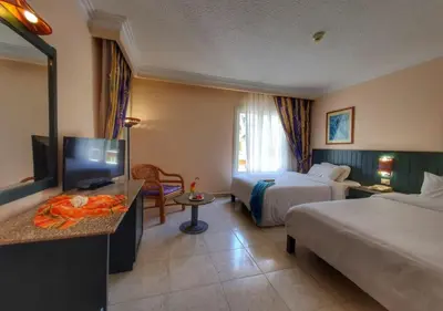 a hotel room with two beds and a flat screen tv at Palm Beach Resort Families and Couples only in Hurghada