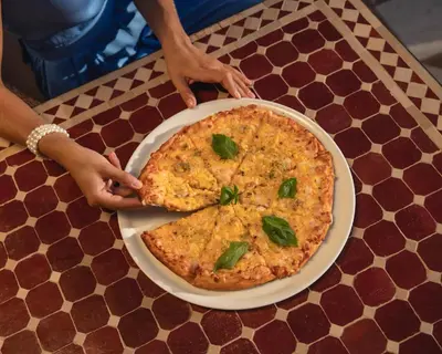 a pizza on a plate on a table at Grand Waterworld Makadi - Couples and Families Only in Hurghada