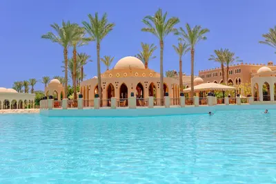 a pool in front of a resort with palm trees at Makadi Palace - Couples and Families Only in Hurghada