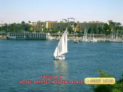 a sailboat on the water in a lake with buildings at Sunny Luxor in Luxor