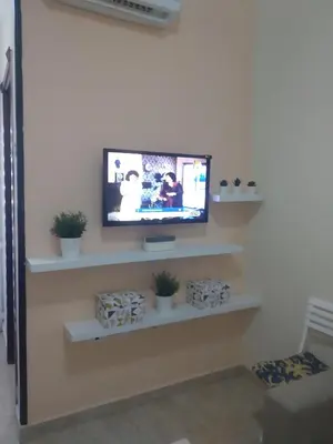 a flat screen tv on a wall with white shelves at Budget studio near El Gouna and Kite station in Hurghada