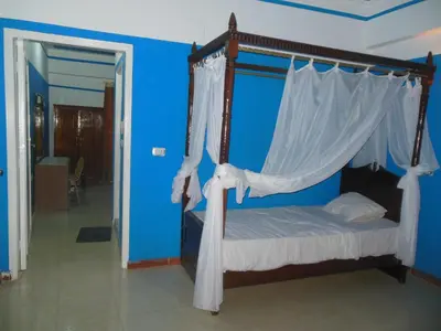 a bedroom with a canopy bed with a blue wall at Cleopatra Hotel Luxor in Luxor