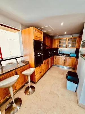 a kitchen with wooden cabinets and a black refrigerator at Aprtment at Abu Tig Marina - MP6 in Hurghada