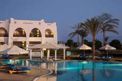 a hotel with a swimming pool with chairs and umbrellas at Hilton Marsa Alam Nubian Resort in Abu Dabab