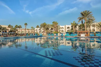 a large swimming pool with palm trees and buildings at Arabia Azur Resort in Hurghada