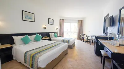a hotel room with two beds and a television at JAZ Palmariva Beach in Hurghada